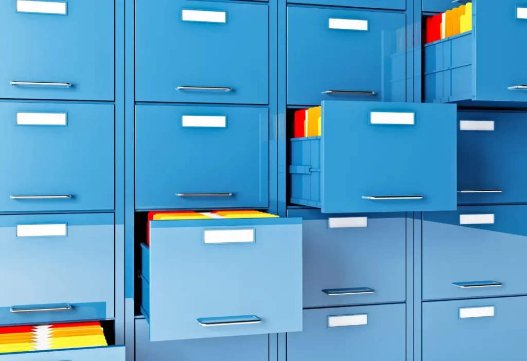 A wall of blue filing cabinets with four pulled out diagonally and multicolored file folders