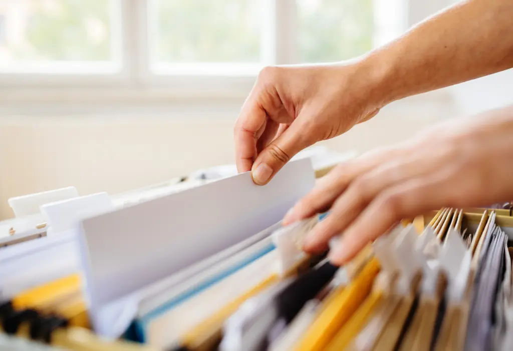 a person pulling paper out of a filing cabinet