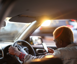 a rideshare driver using a phone with one hand of the wheel