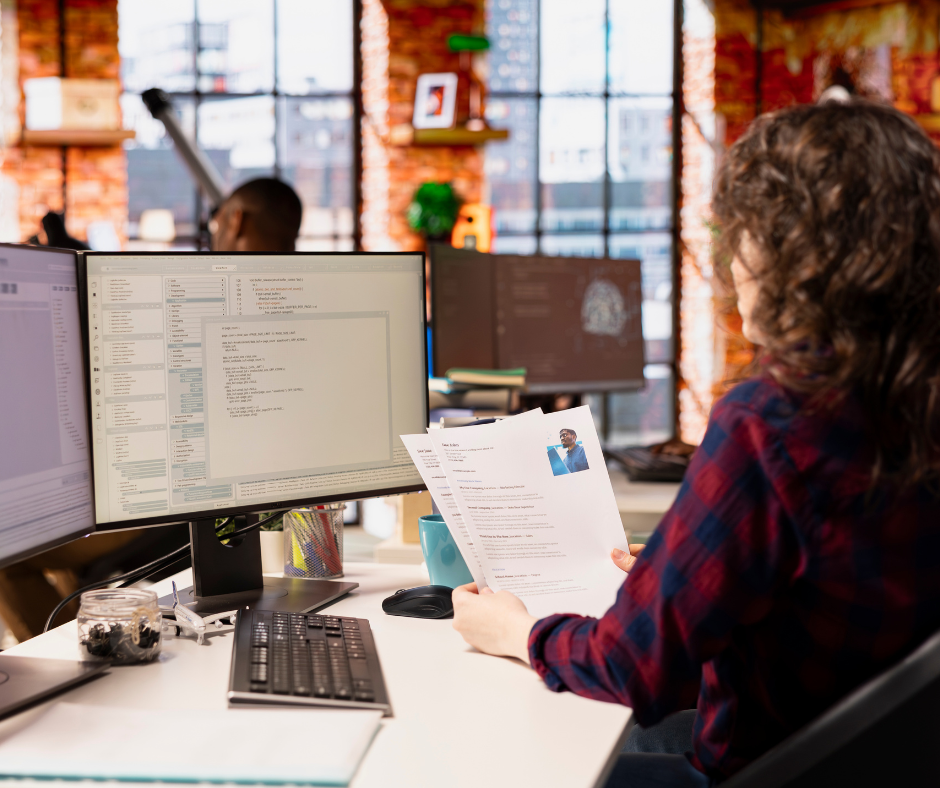 person reviewing resumes in front of computers